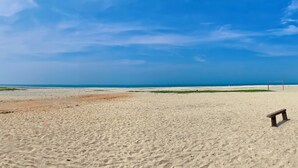 A beach with a wooden bench and a volleyball net. - Pine Beach House (Alappuzha)