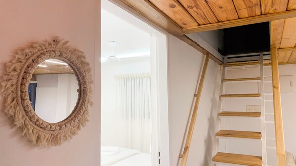 A bedroom with a large mirror, a wooden ladder, and a white bed. - Pine Beach House (Alappuzha)