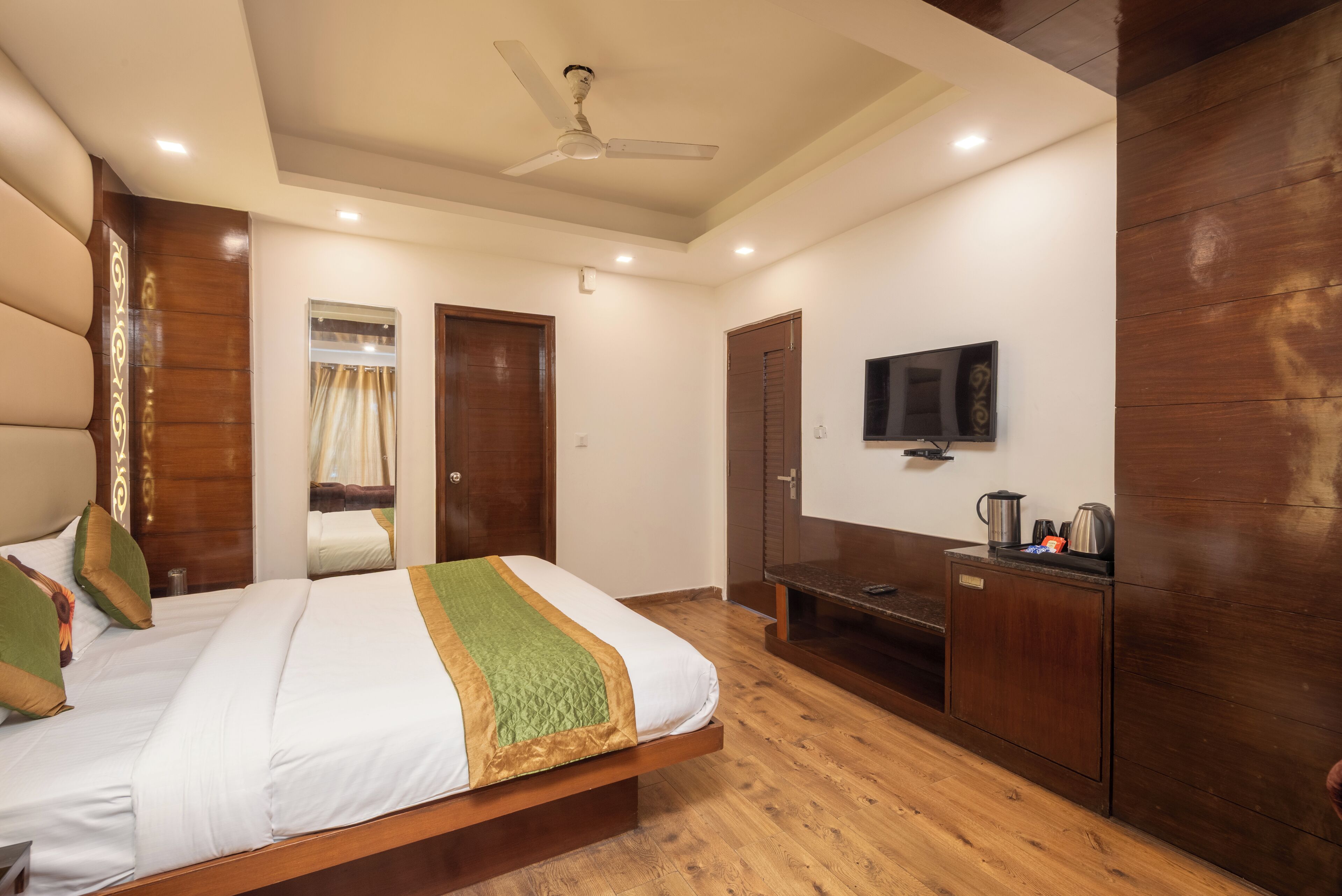 A bedroom with a bed, a television, a wardrobe, and a ceiling fan.