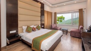 Ein Hotelzimmer mit einem großen Bett, einem Schreibtisch, einem Stuhl und Blick ins Freie.