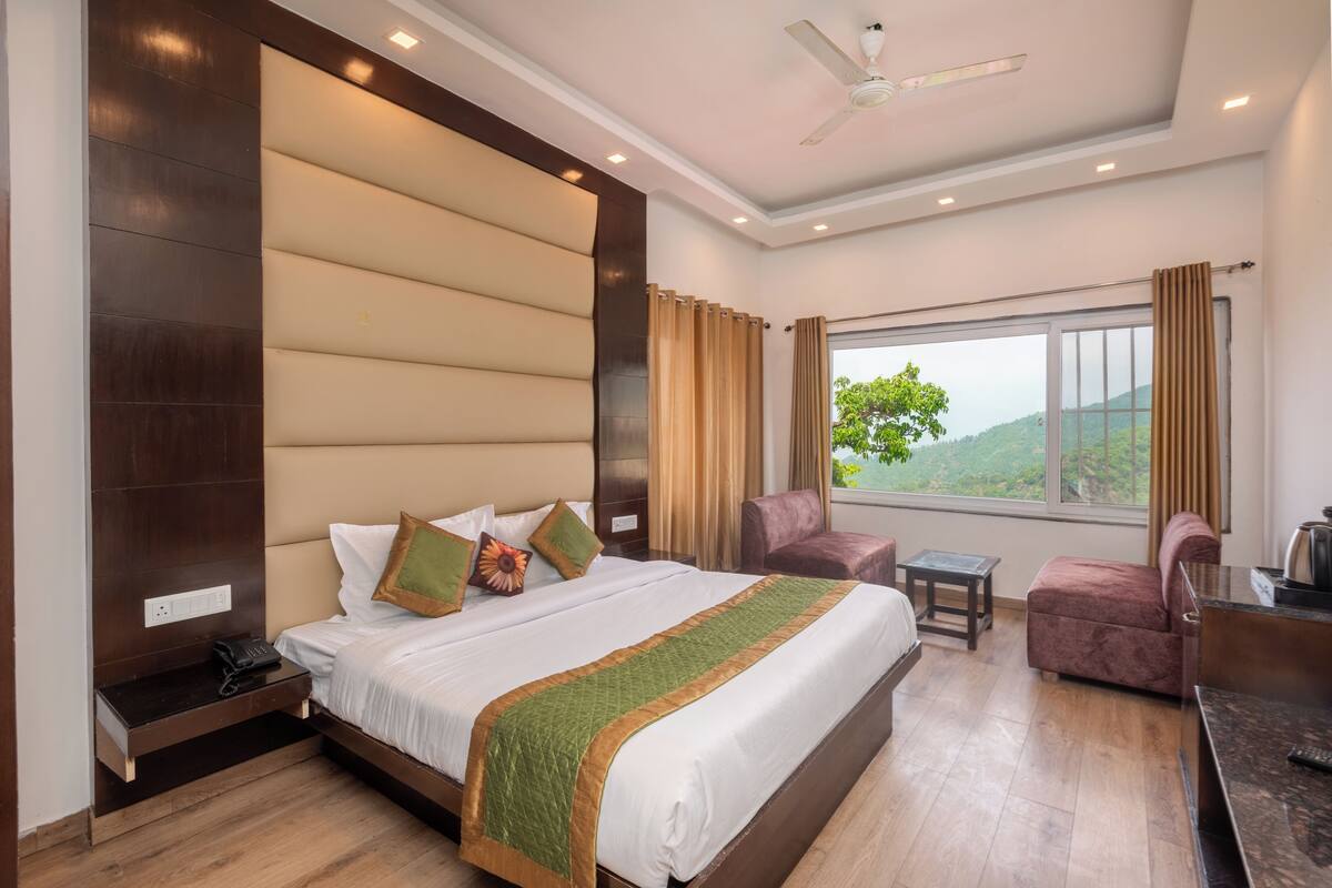 Een hotelkamer met een groot bed, een bureau, een stoel en uitzicht op de omgeving.