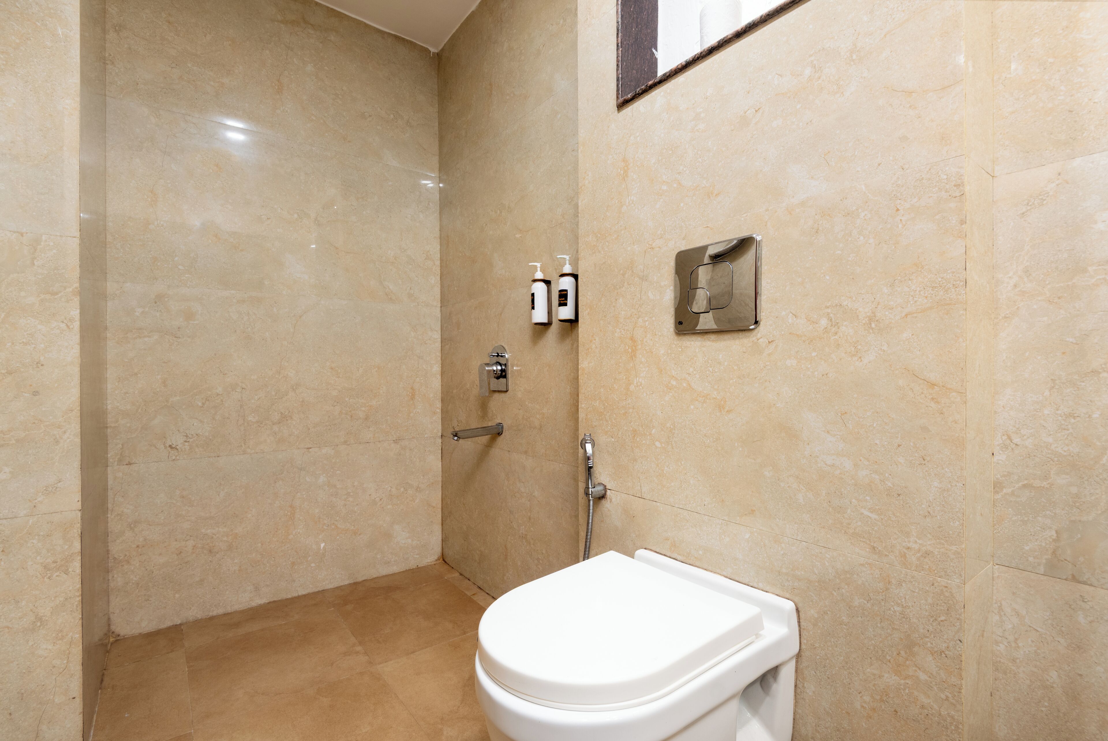 A bathroom with a white toilet, a shower area, and a hand dryer mounted on the wall.