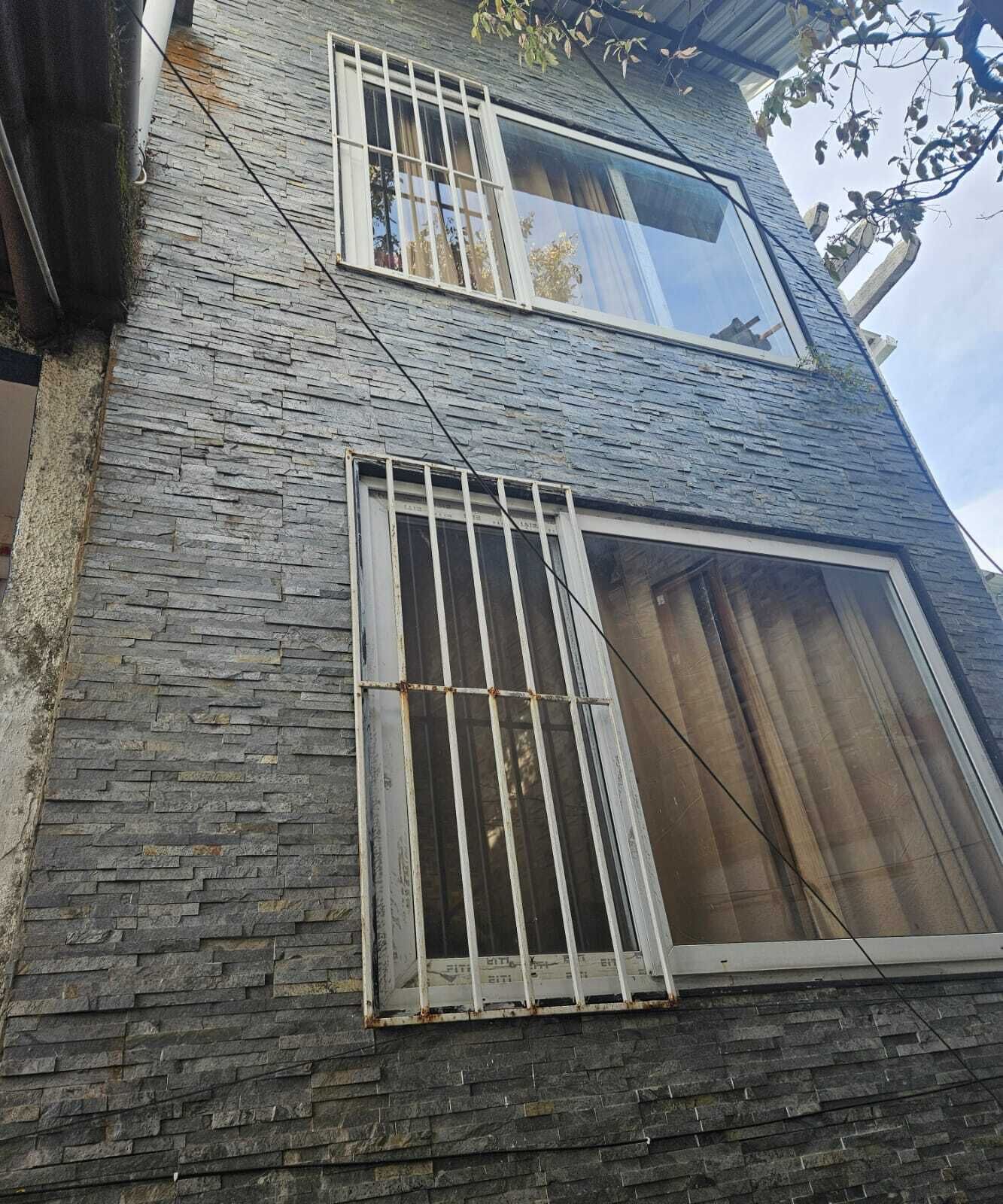 Un edificio de varios pisos con fachada de piedra y ventanas con barrotes.