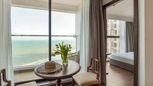 A balcony with a view of the ocean, a table with a vase of flowers, and a sofa. - Cozy Tranquility Mandala Retreat (Mui Ne)