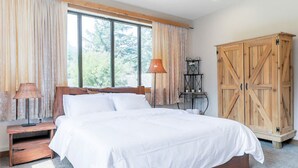 Un dormitorio con una cama grande, un armario de madera y una ventana con cortinas.