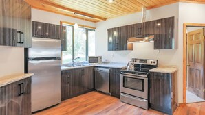Una cocina moderna con vigas de techo de madera, electrodomésticos de acero inoxidable y armarios de madera oscura.