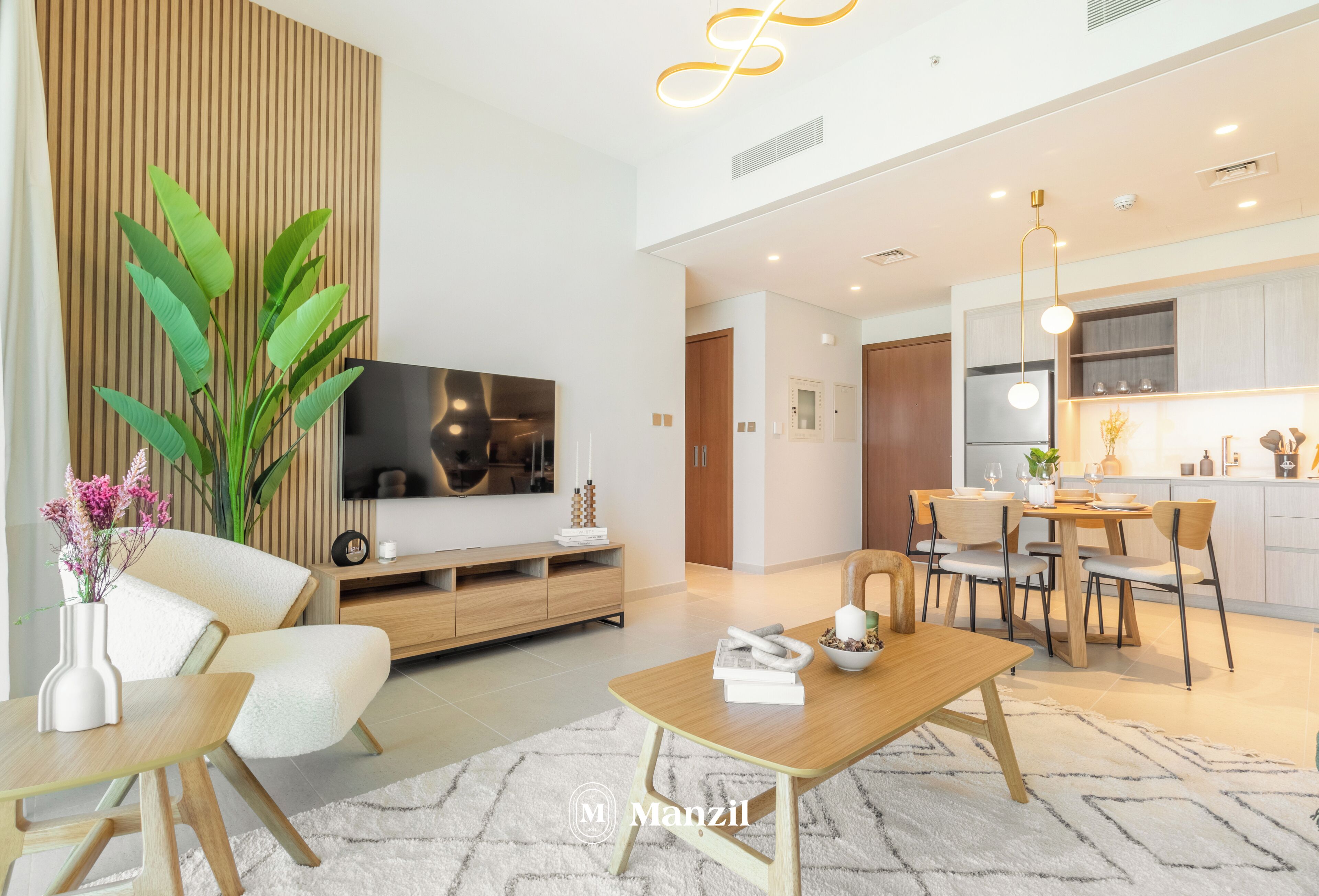 A modern living room with a flat-screen TV, a dining area, and a kitchen.