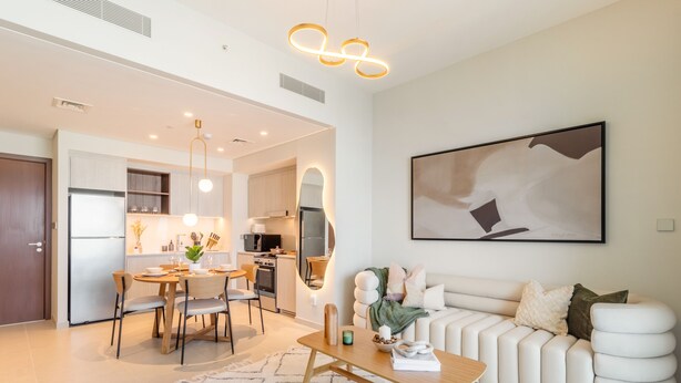 Une cuisine moderne avec un coin repas, un salon doté d’un canapé et d’une table basse, et un grand tableau abstrait accroché au mur.