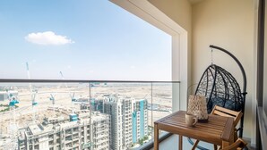 Un balcon donnant sur un chantier de construction, avec une chaise suspendue.