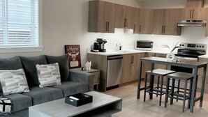 A modern kitchen with wooden cabinets, a built-in microwave, and a stainless steel oven. - Victoria luxury one bedroom suite (Langford)