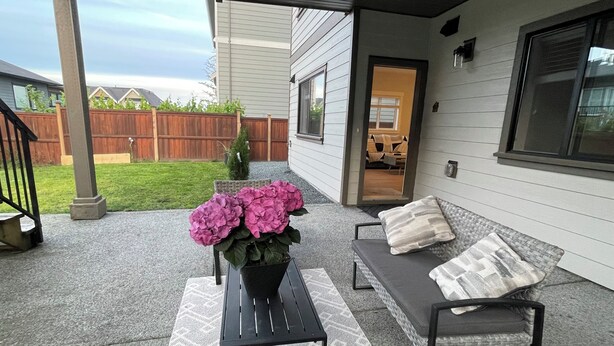 A covered patio with a seating area, a potted plant, and a view of the backyard. - Victoria luxury one bedroom suite (Langford)