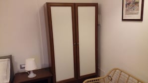 A room with a wardrobe, a bedside table with a lamp, and a wicker chair. - IL FILO DI ARIANNA (Ricco del Golfo di Spezia)