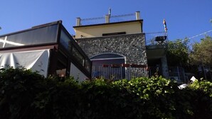 A building with a stone facade, a metal balcony, and a gated entrance. - IL FILO DI ARIANNA (Ricco del Golfo di Spezia)