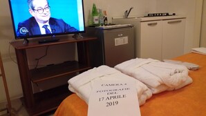 A hotel room with a bed, a TV displaying a news program, a minibar, and a sign indicating the room number and date. - IL FILO DI ARIANNA (Ricco del Golfo di Spezia)
