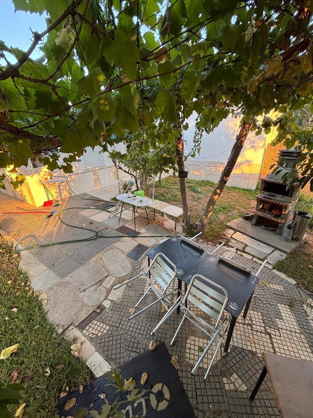 Eine Terrasse im Freien mit Tisch, Stühlen, einem Grill und Blick auf ein Gewässer.