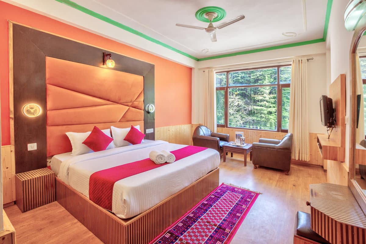 Habitación de hotel moderna con una cama grande, ventilador de techo, escritorio de madera y vistas al exterior.