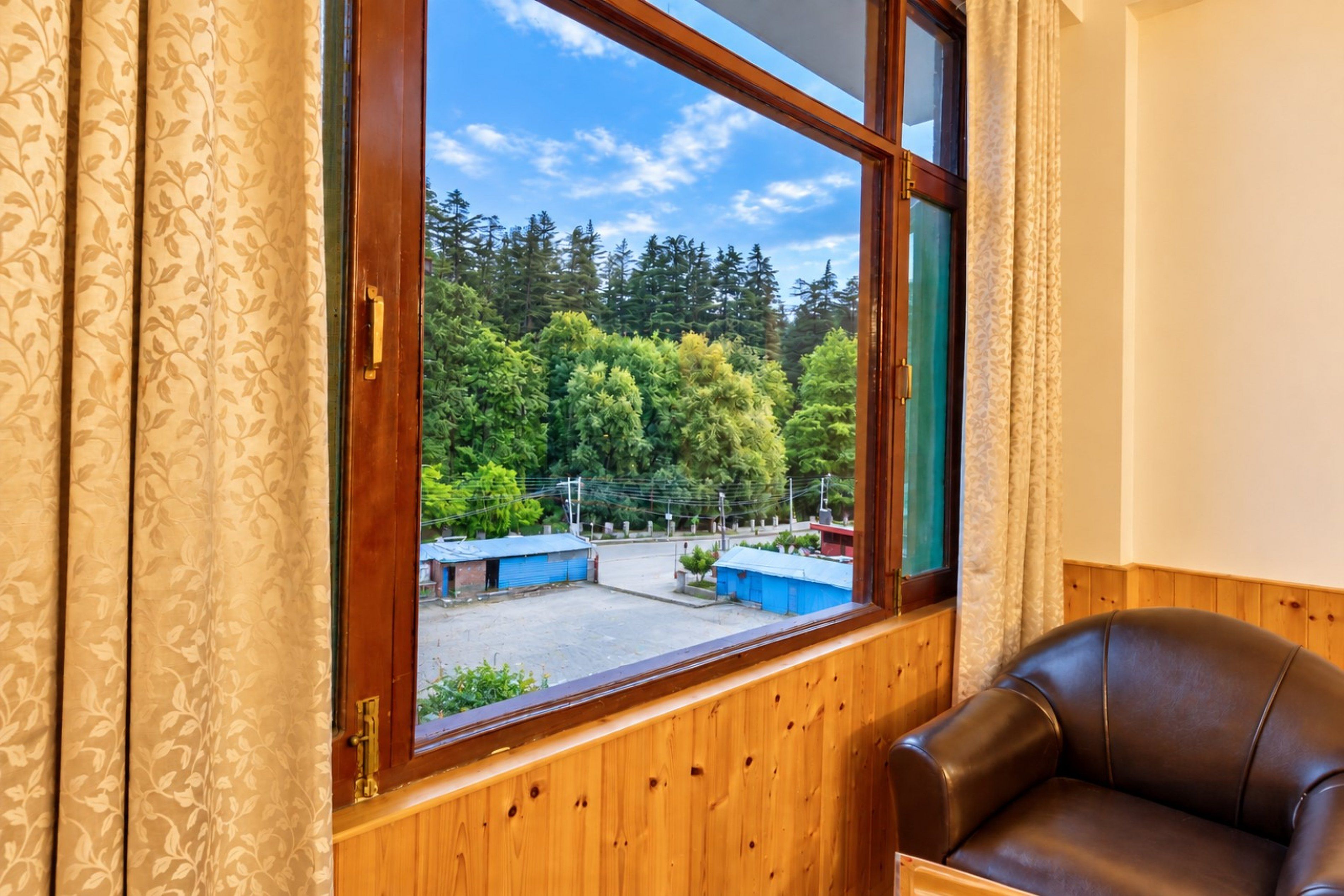 Una habitación con un ventanal grande, paneles de madera y un sillón de cuero.