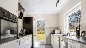 A modern kitchen with stainless steel appliances, a large window, and a view of the outdoors.