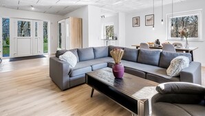 A modern living room with a grey sectional sofa, a coffee table, and a dining area with a table and chairs.