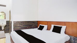 Ein ordentlich bezogenes Bett mit schwarz-weißer Tagesdecke, einem hölzernen Kopfteil und einer Wand mit Steinmuster im Hintergrund.