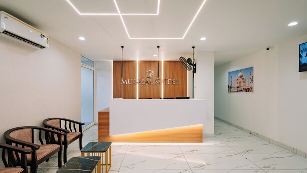 Un área de recepción con un mostrador de madera, una lámpara moderna y un cuadro en la pared.