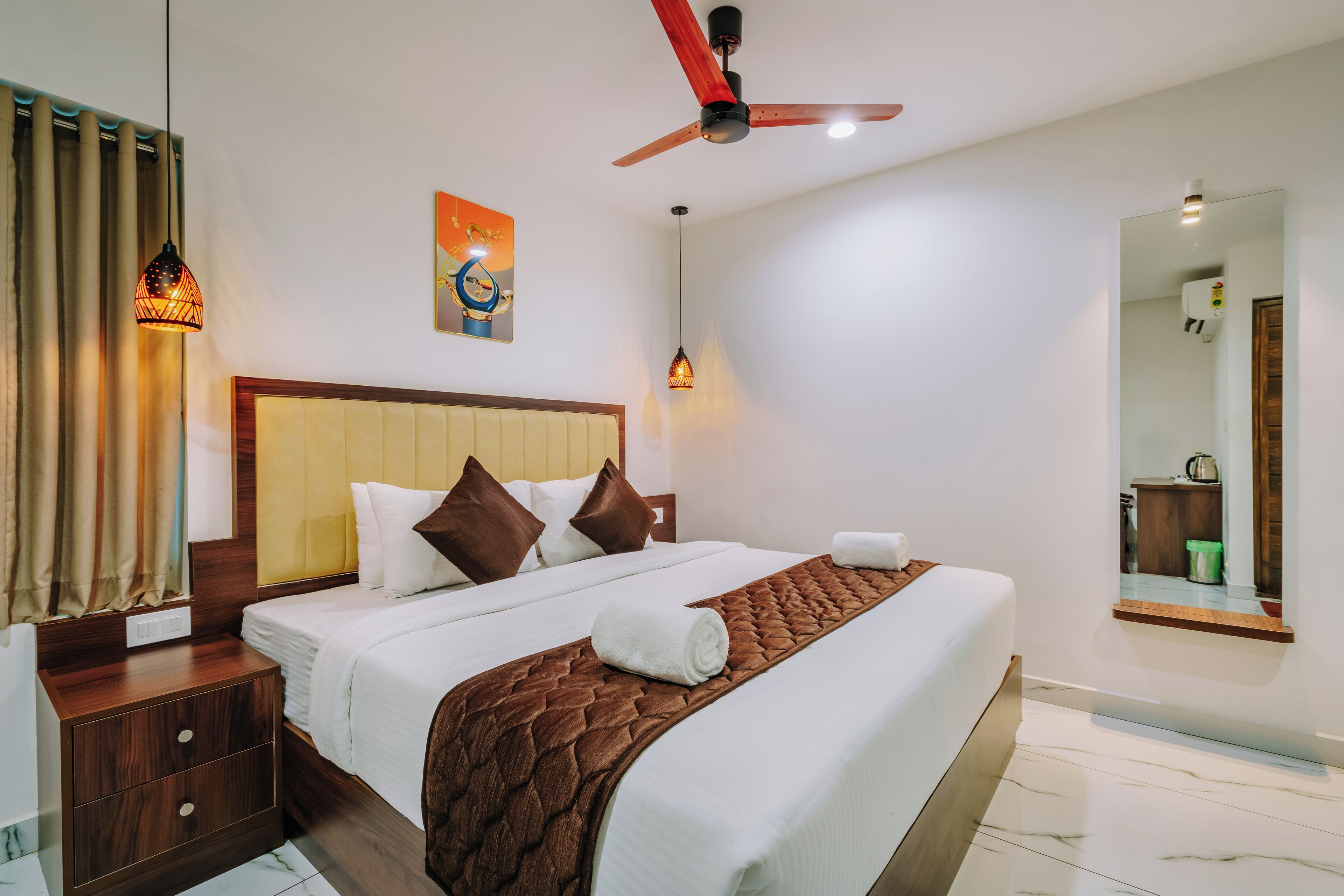 A hotel room with a bed, wooden nightstand, and a ceiling fan.