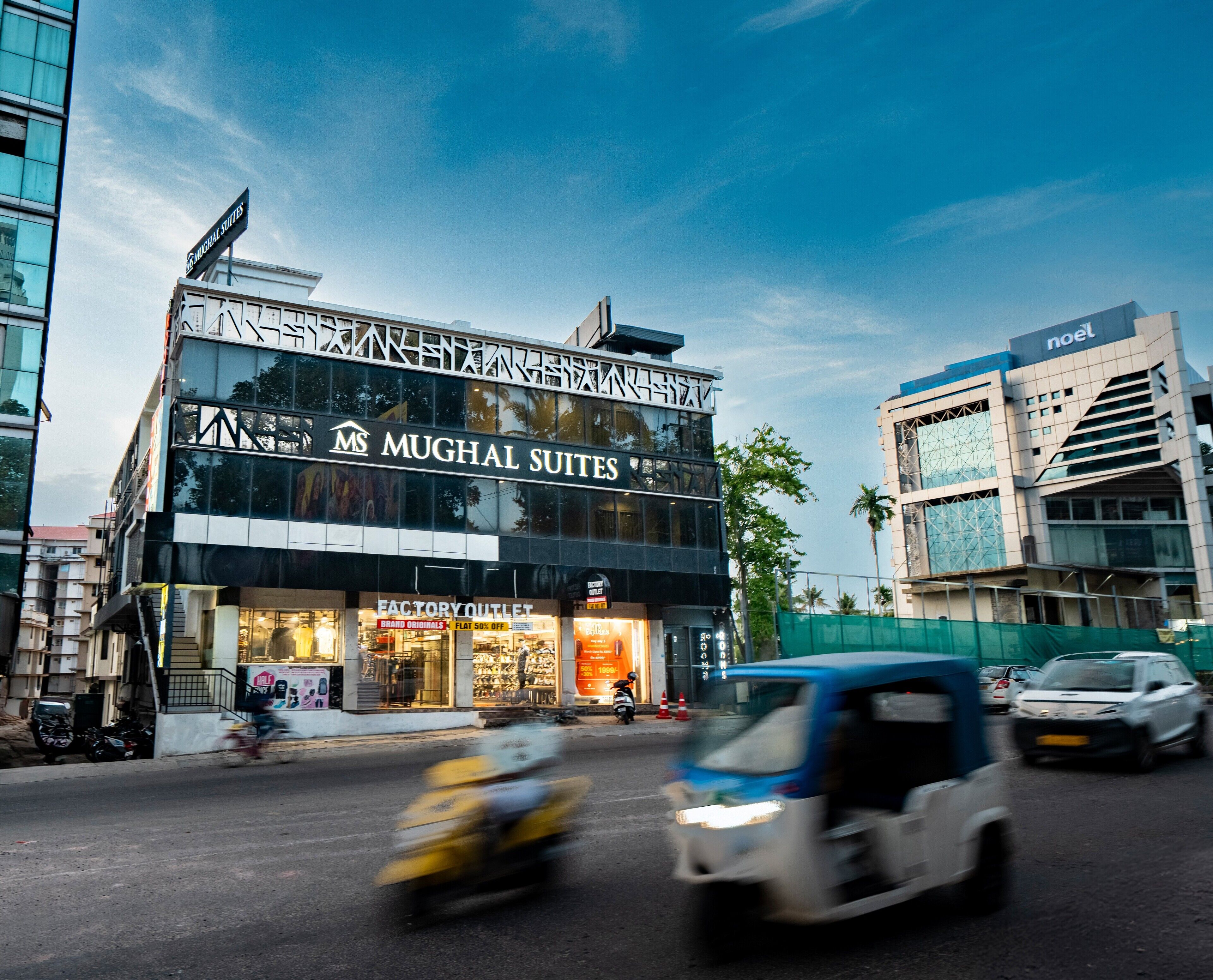 Un edificio de varios pisos con letreros que indican 'Mughal Suites' y 'Factory Outlet'.