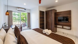 Una habitación de hotel moderna con una cama grande, un televisor montado en la pared y un balcón con vistas a zonas verdes.