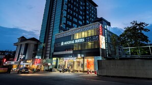 A hotel with a modern facade, a sign for 'Mughal Suites', and a 'Factory Outlet' store. - MUGHAL SUITES (Kanayannur)