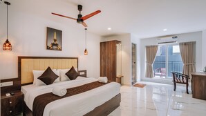 Habitación de hotel con una cama grande, ventilador de techo, una imagen de la Torre Eiffel y vistas al exterior.