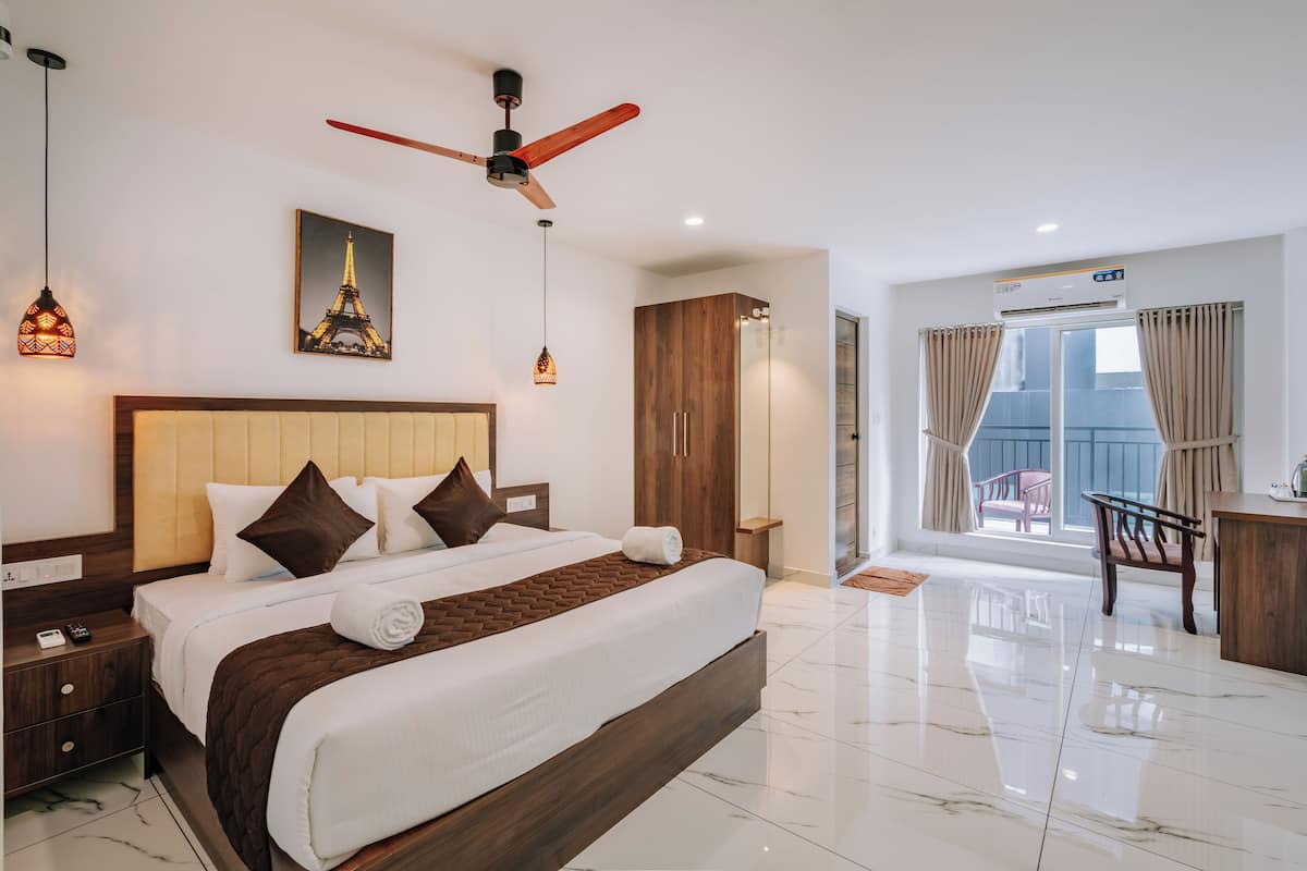 A hotel room with a large bed, a ceiling fan, a picture of the Eiffel Tower, and a view of the outdoors.