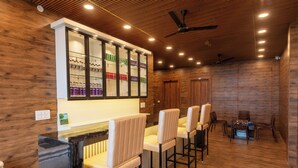 A bar area with a wooden interior, bar stools, and a glass display case with beverages. - Mountain Villa Mussoorie  (Mussoorie)