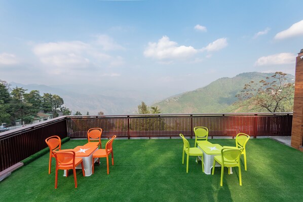 A balcony with green artificial grass, two tables, and four chairs. - Mountain Villa Mussoorie (Mussoorie)