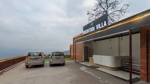A hotel entrance with a sign reading "Mountain Villa" and two parked cars in front. - Mountain Villa Mussoorie  (Mussoorie)