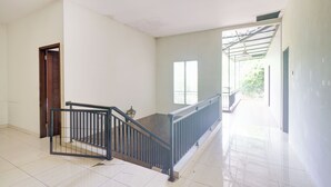 A spacious hallway with a staircase, a door, and a window. - Hotel O Bogor near Taman Safari formerly Hotel Rudian 2 (Cisarua)