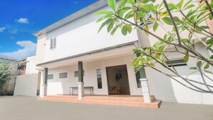A two-story white building with a covered porch and a small garden area. - Hotel O Bogor near Taman Safari formerly Hotel Rudian 2 (Cisarua)