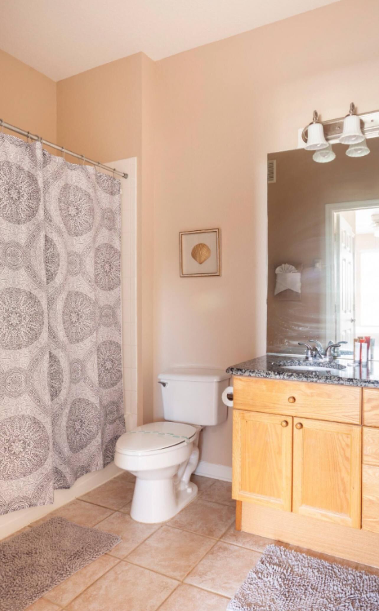 A bathroom with a toilet, a shower curtain, a sink with a mirror, and a towel rack.