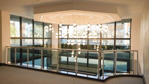 A modern interior with a glass railing, a geometric ceiling light fixture, and large windows. - Zade Life OTEL (Gaziantep)