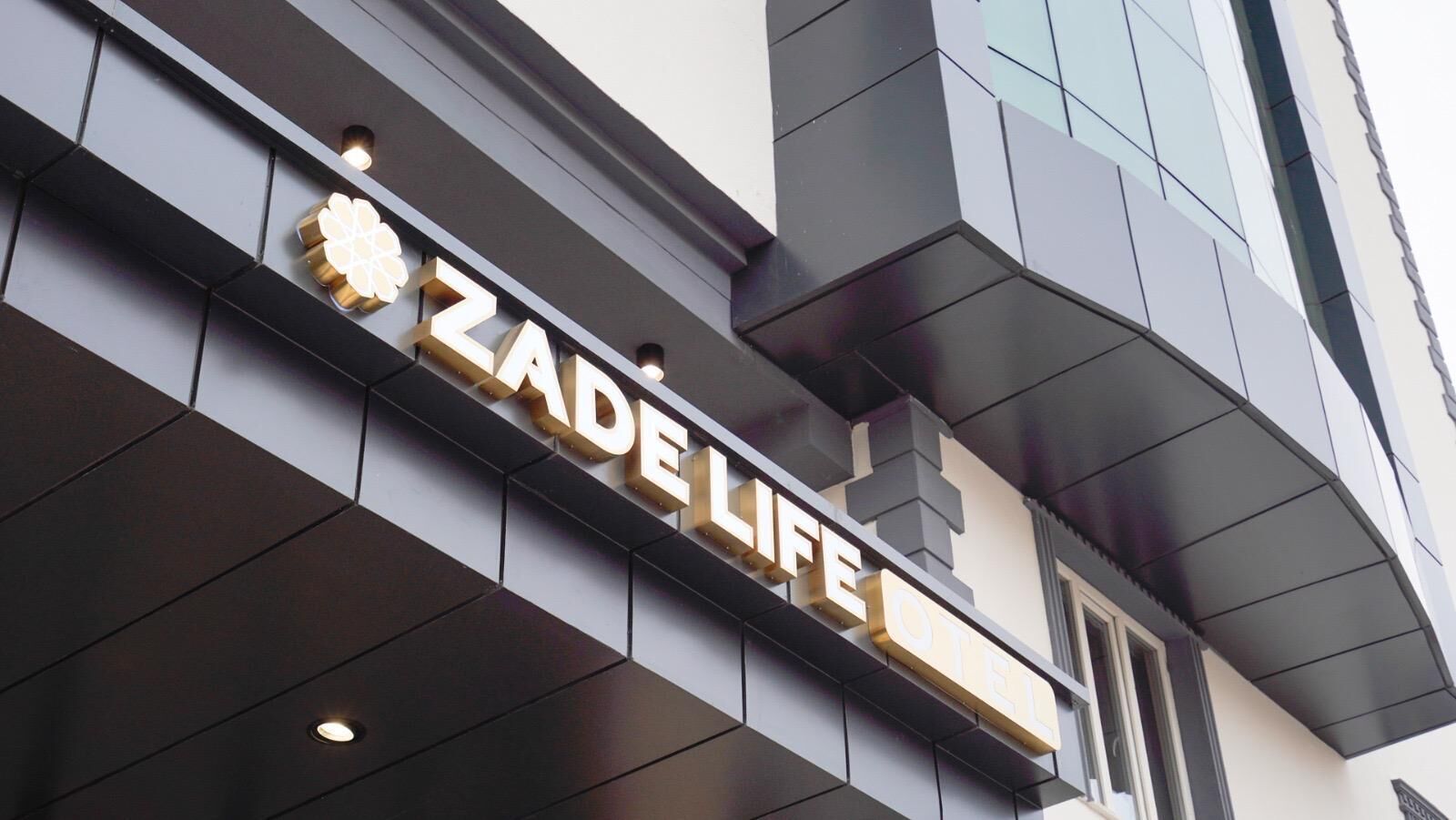 Exterior do hotel Zade Life, com seu nome iluminado em letras douradas.