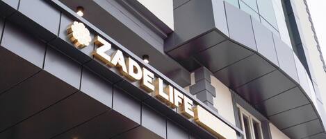 Fachada del hotel Zade Life, con su nombre iluminado en letras doradas grandes.