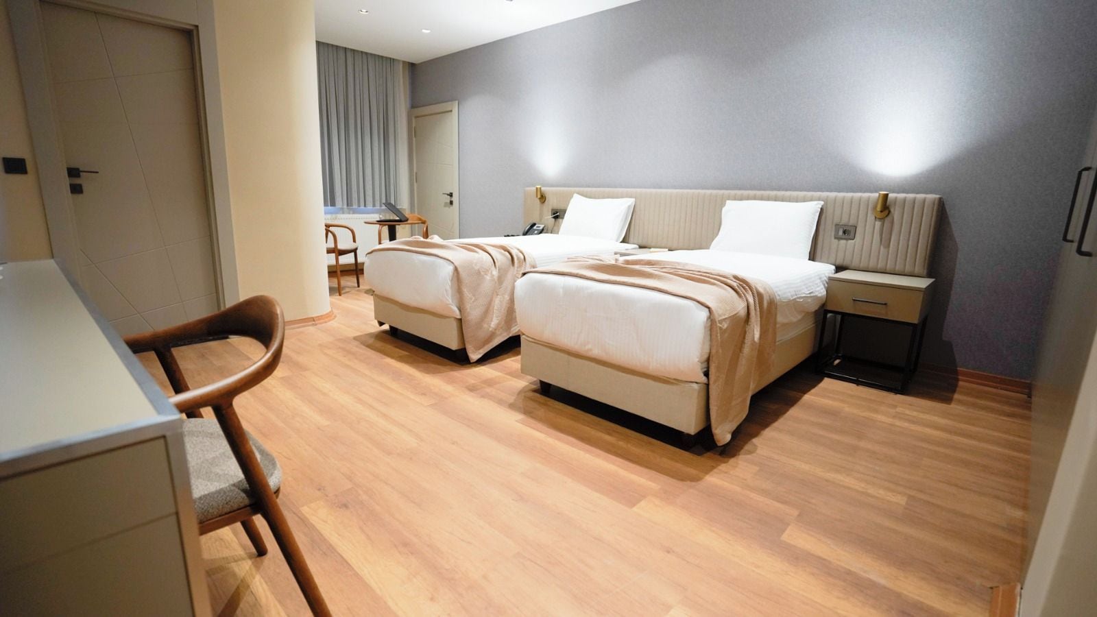 Ein Hotelzimmer mit zwei Betten, einem Schreibtisch und einem Stuhl.
