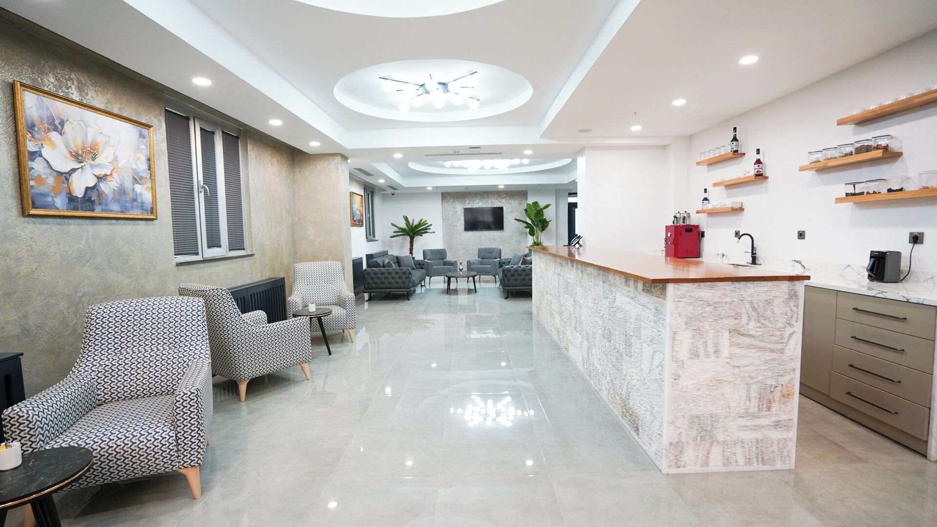 A modern hotel lobby with a reception desk, seating area, and a large painting on the wall.
