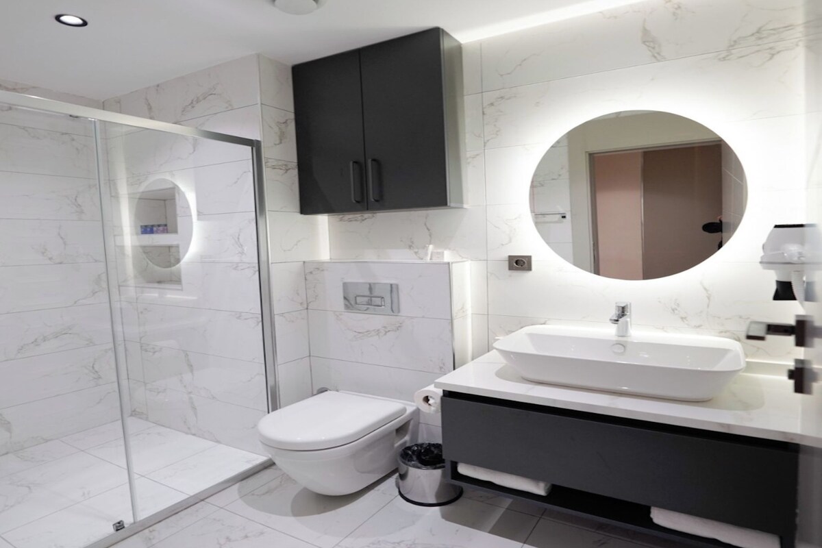 Une salle de bain moderne avec une douche à parois de verre, des toilettes, un lavabo avec un miroir et un meuble de rangement.