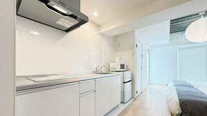 Μια σύγχρονη κουζίνα με λευκά ντουλάπια, ένα φούρνο μικροκυμάτων και έναν νεροχύτη.