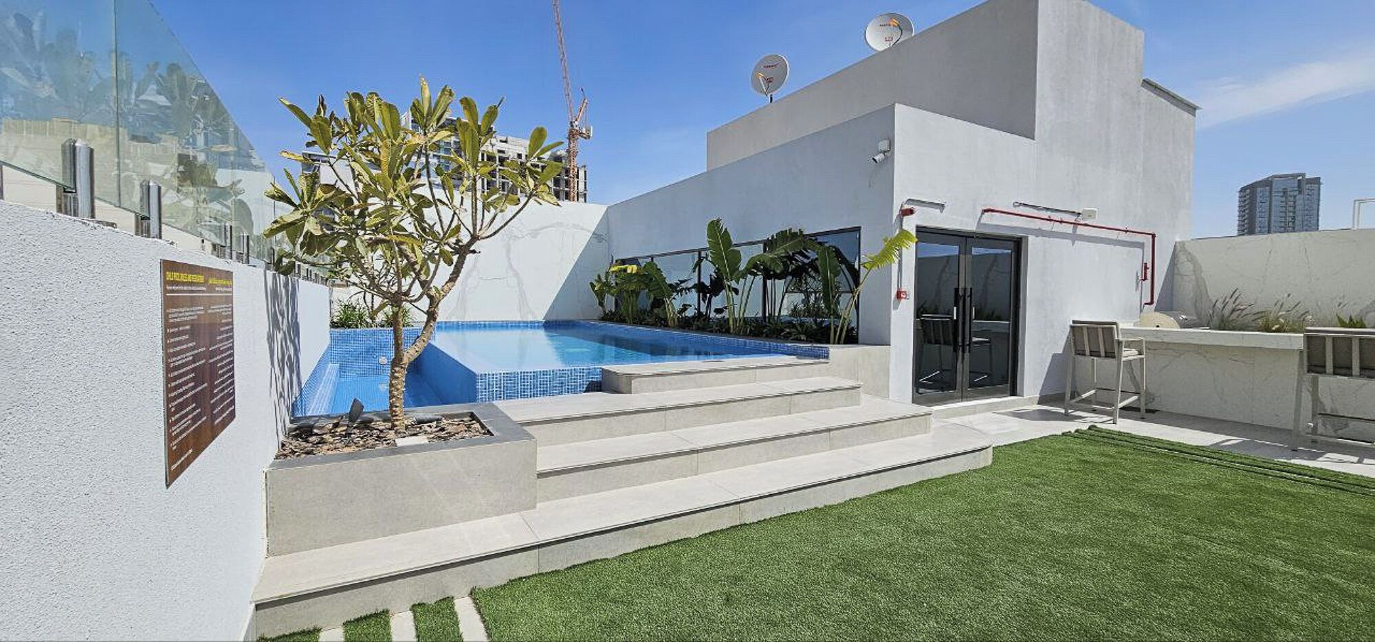 A modern house with a swimming pool, a small garden, and a staircase leading to the entrance.
