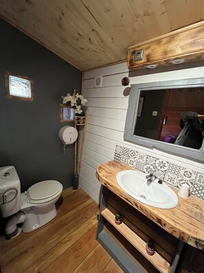 Et lille badeværelse med en trækommode, toilet og spejl.