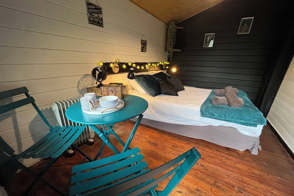 A cozy room with a bed, a small table with a chair, and a radiator.