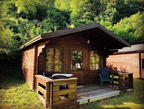 En rustik hytte med veranda, et bord og stole.