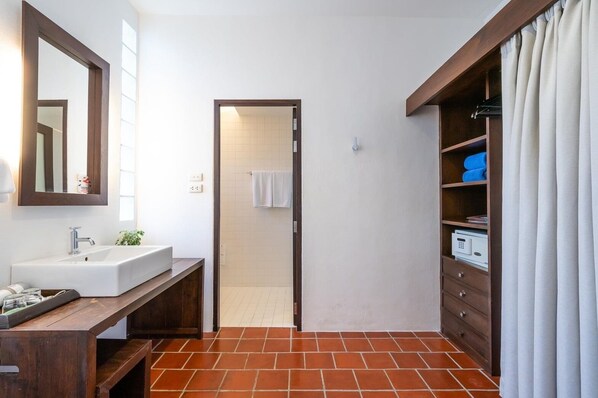 A bathroom with a white sink, a mirror, a towel rack, a shower area, and a wooden cabinet with shelves. - Aqua Beads Samed (Rayong)