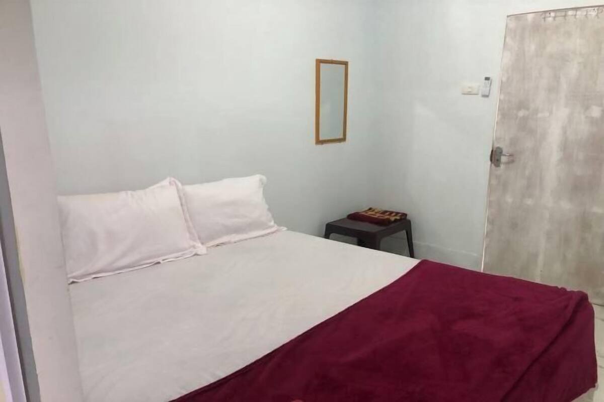 A bedroom with a bed, a small table, a mirror, and a door.